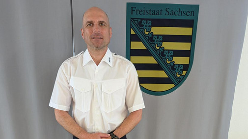 Sven Riemer vor dem Wappen des Freistaates Sachsen